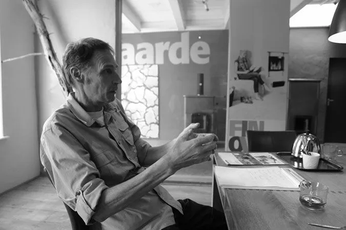 Jan Bos im Gespräch an einem Tisch im Ausstellungsraum, Schwarz-Weiß-Foto